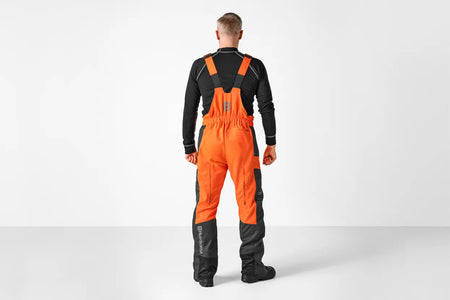 Husqvarna Classic overalls med savbeskyttelse – Person facing away wearing Husqvarna chainsaw trousers.